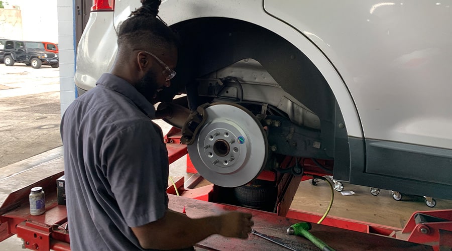 Maxi Auto Repair and Service’s technician servicing the brakes of a suspended car. Concept image of “How to Properly Maintain Your Car’s Brakes” | Maxi Auto Repair and Service - Hodges in Jacksonville, FL.