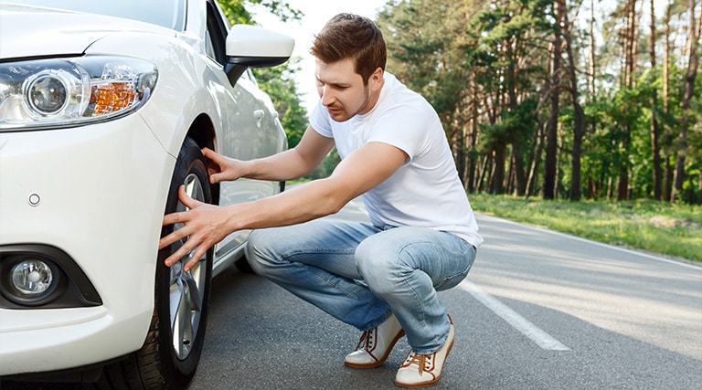 a driver checking his tire, is it time to get new tire | Maxi Auto Repair