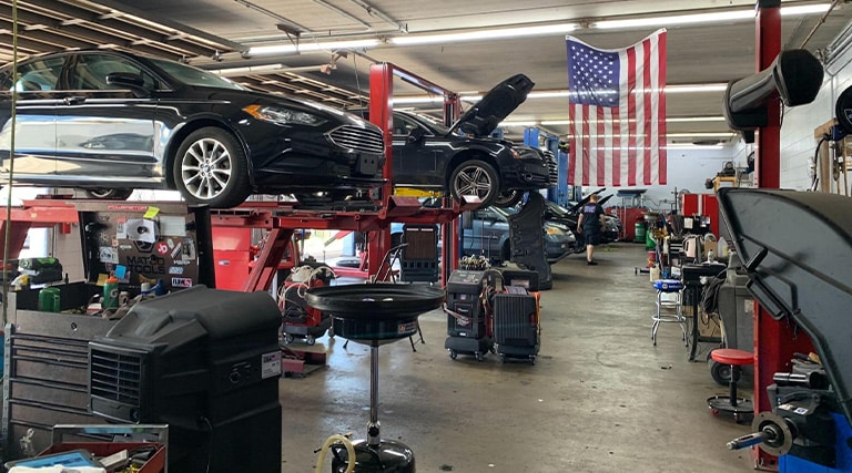 Holiday Vehicle Safety Check | Maxi Auto Repair Jacksonville | $25 Comprehensive Package. Comprehensive maintenance being performed on cars on lifts in shop bay.