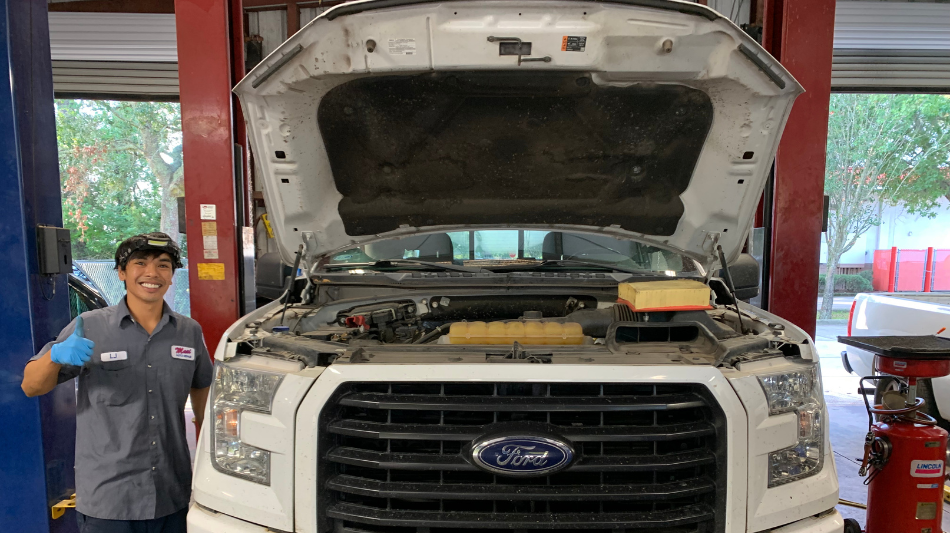 Trusted Mechanic Near Jacksonville, FL | Maxi Auto Repair | Quality Auto Repair. Image of happy mechanic at shop putting new tire on truck in shop.