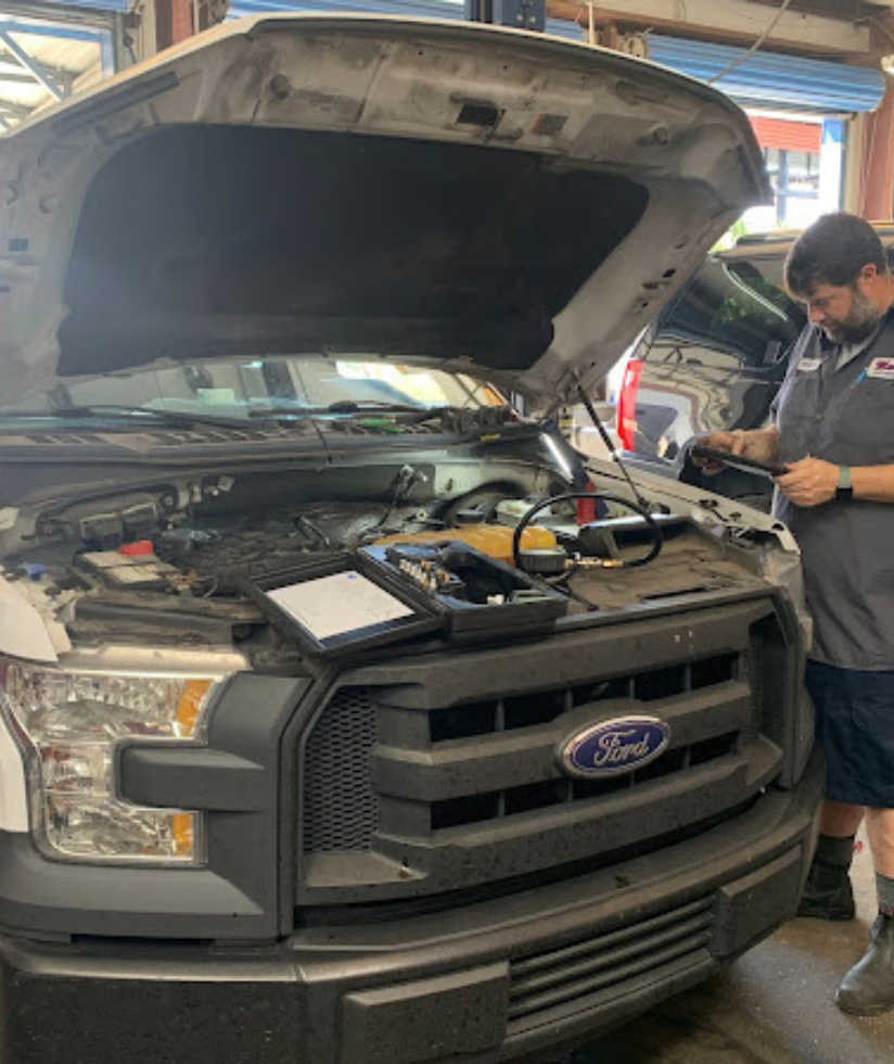 Jacksonville's Ford Repair Specialists Maxi Auto Repair Quality Service. Image of mechanic repairing ford truck in shop.