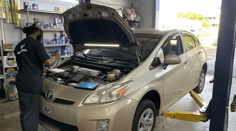 Signs your car needs a tune up near me in Jacksonville, FL with Maxi Auto Repair. Image of mechanic in shop performing a tune up replacing an old engine air filter with a new one on a Toyota prius hybrid vehicle in shop.