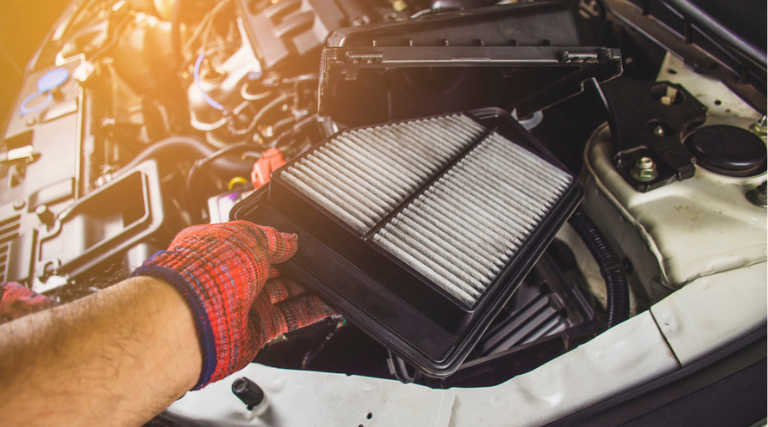 Filter Replacement near me in Jacksonville, FL at Maxi Auto Repair. Image of a mechanic's hand replacing a car air filter in the filter socket of a car engine during car maintenance.