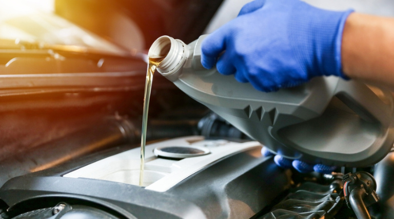 Oil Change Service near me in Jacksonville, FL at Maxi Auto Repair. Image of a technician's hand pouring oil into the engine during an oil change service performed by an expert