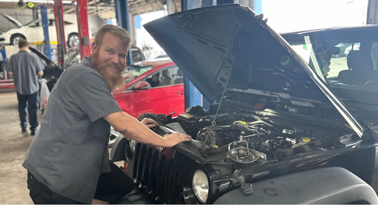 Vehicle Tune-Up in Jacksonville, FL by Maxi Auto Repair and Service. Image of a master technician with an open hood Jeep undergoing a vehicle tune-up.